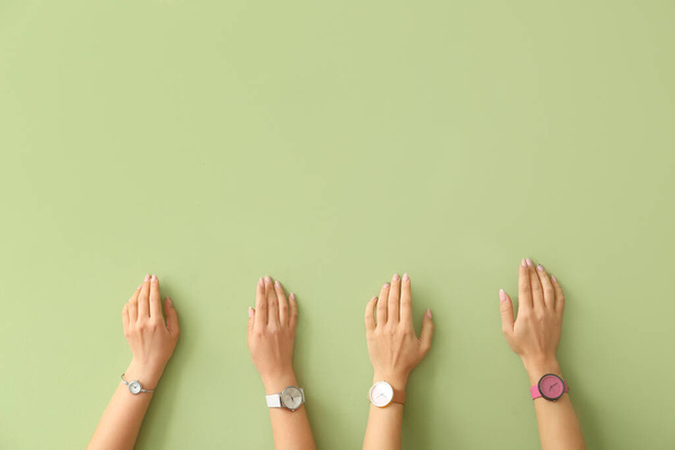 Женские руки с наручными часами на цветном фоне - Фото, изображение