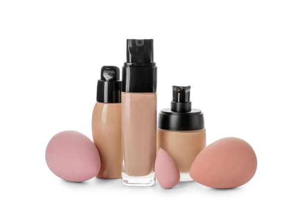 Flessen van make-up foundation en sponzen op witte achtergrond - Foto, afbeelding
