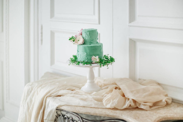 Wedding cake with soft green cream and decorated with fresh flowers in a beautiful interior. Cake in the style of boho - Фото, изображение