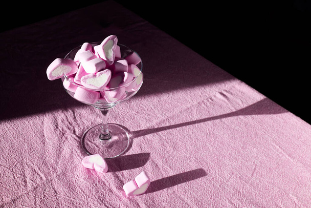 Forma de coração rosa, sabor de morango Marshmallow na placa branca na mesa com toalha de mesa rosa. Rosas no fundo. Tema do amor, Conceito de Valentine. - Foto, Imagem