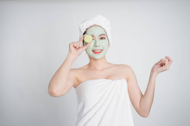 Asiatico donna tenere fresco cetrioli e sorriso relaxedly con un facciale maschera. - Foto, immagini