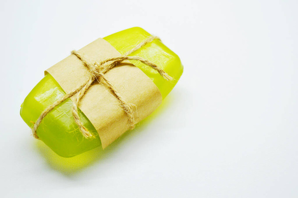 Green soap tied with rope and brown paper lies on a white background - Photo, Image