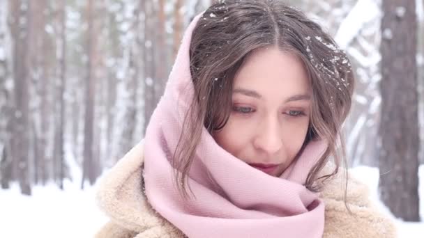Portret van een jonge aantrekkelijke vrouw in het bos. Modieuze jonge vrouw in een eco bont jas in een park in de winter poseren en glimlachen. - Video