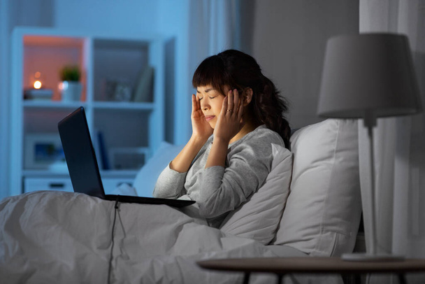 stressed woman with laptop working in bed at night - Photo, Image