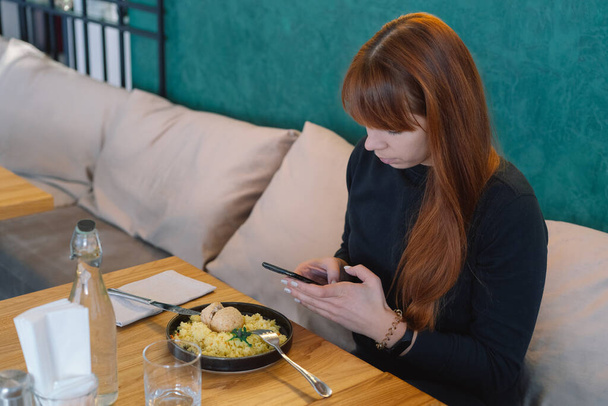 Güzel kız kafede yemek yerken cep telefonu kullanıyor. - Fotoğraf, Görsel