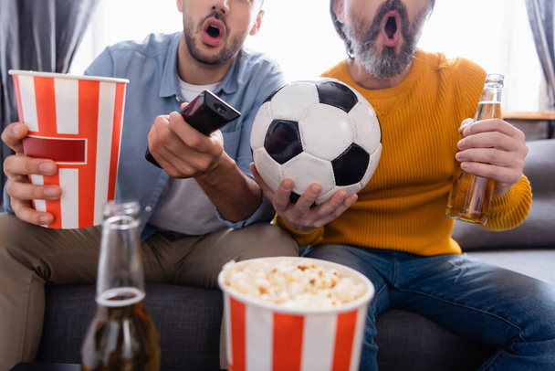 vista parcial del padre y el hijo emocionados viendo el partido de fútbol en la televisión en casa, fondo borroso - Foto, Imagen
