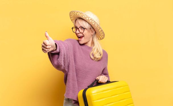 blonde woman feeling proud, carefree, confident and happy, smiling positively with thumbs up - 写真・画像