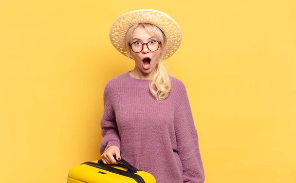 blonde woman looking very shocked or surprised, staring with open mouth saying wow - 写真・画像