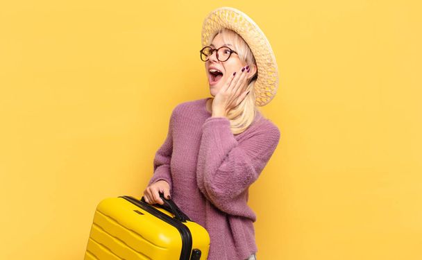 blonde woman feeling happy, excited and surprised, looking to the side with both hands on face - Photo, image