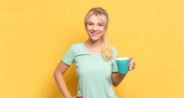 blonde woman smiling happily with a hand on hip and confident, positive, proud and friendly attitude - Foto, imagen
