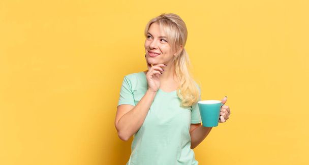 blonde woman smiling happily and daydreaming or doubting, looking to the side - Фото, изображение
