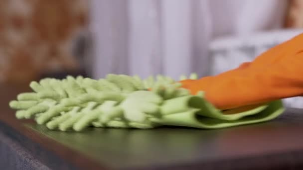 Vrouwelijke hand in rubber oranje handschoenen veegt een houten oppervlak met microvezel doek - Video