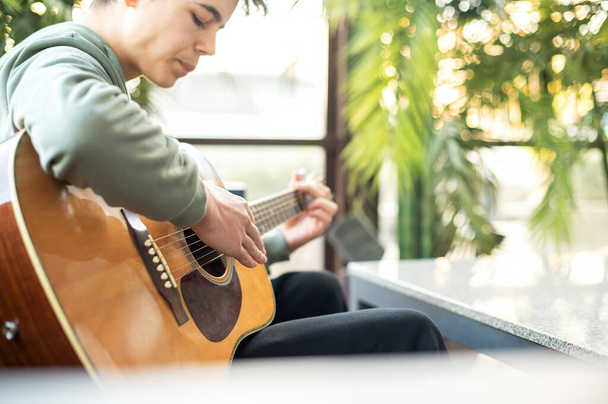 Un uomo sta suonando la chitarra, piante sullo sfondo - Foto, immagini