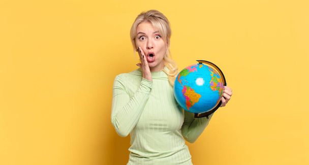 blonde woman feeling shocked and scared, looking terrified with open mouth and hands on cheeks - Photo, Image