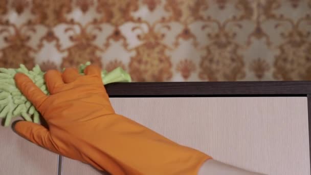 Mano femminile in gomma arancione guanti pulisce una superficie di legno con microfibra Rag - Filmati, video