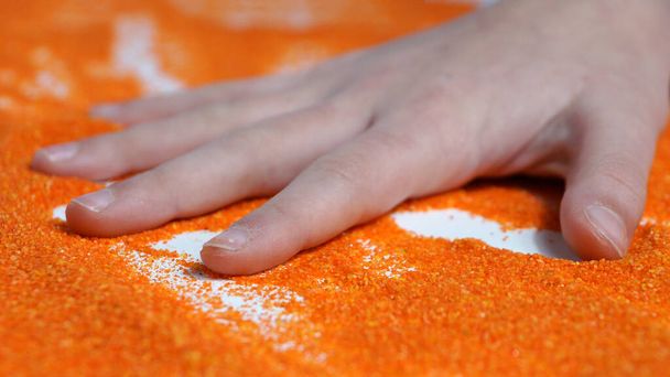 砂療法オレンジの運動砂の上の子供の手. - 写真・画像