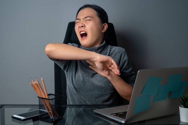 Femme asiatique était malade de fièvre, travaillant sur un ordinateur portable au bureau. isolé sur fond gris. - Photo, image