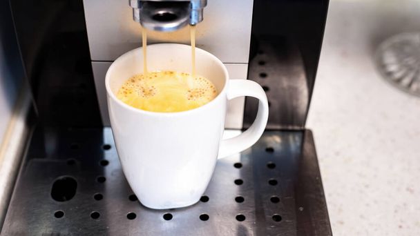 Καφετιέρα ρίχνει καφέ με σε ένα φλιτζάνι - Φωτογραφία, εικόνα