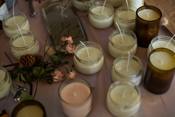 Soy Candles poured into recycled bottles and jars. Many soy wax candles together on store or workshop background. . Ecological and vegan business. - Photo, Image