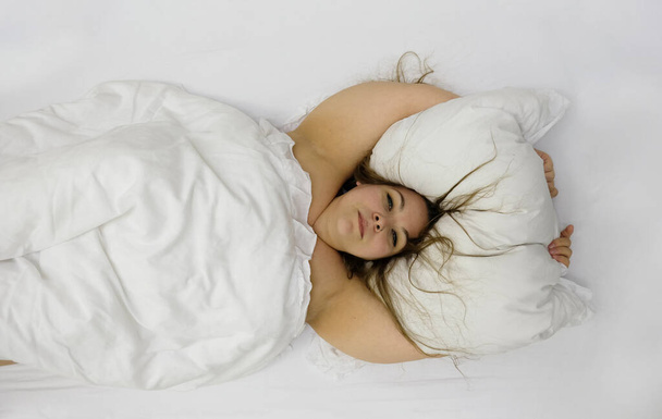 Πορτρέτο ενός αισιόδοξου θετική χαρούμενη παχουλό γυναίκα στο κρεβάτι αγκαλιάζει μαξιλάρι. Μελαχρινή χαριτωμένο συν μέγεθος κορίτσι χαλαρώνοντας στην κρεβατοκάμαρα, αντίγραφο χώρου - Φωτογραφία, εικόνα