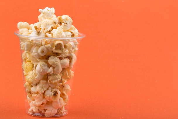 Куча вкусного соленого попкорна, изолированного на оранжевом фоне - Фото, изображение