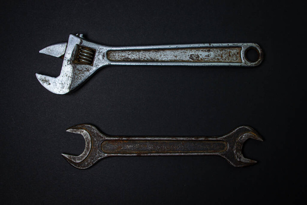 Clé et clé réglable sur fond noir. De vieux outils de travail. Outils en acier - Photo, image