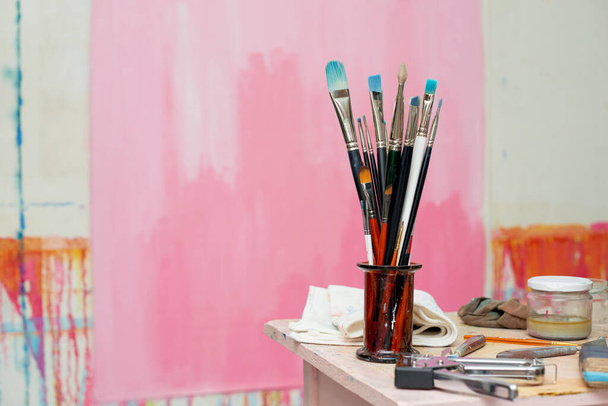 Τέχνη στούντιο τάξη πινέλα ζωγραφικής κοντά σε ροζ φόντο - Φωτογραφία, εικόνα