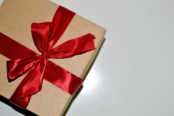 Загорнута вінтажна подарункова коробка з червоним стрічковим бантом ізольовано на білому. Вид зверху
 - Фото, зображення