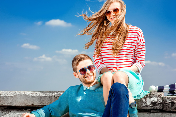 Hymyilevä pari istuu katolla syleillen ja hymyillen
  - Valokuva, kuva