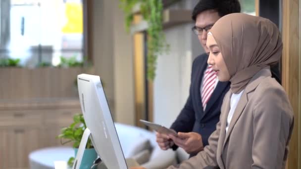 Manažer trénuje muslimský personál. Vážný muž manažer dohlížející na muslimskou zaměstnankyni pomáhá s počítačovým problémem. - Záběry, video