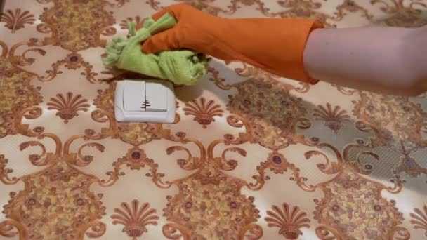 Weibliche Hände in orangefarbenen Gummihandschuhen wischen zu Hause Lichtschalter ab - Filmmaterial, Video