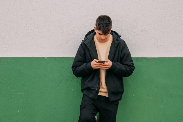 joven adolescente en la pared de la calle con teléfono móvil - Foto, imagen