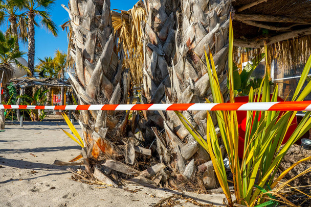 Mediterraan strandrestaurant gesloten om verspreiding van het coronavirus Covid 19 te stoppen. Het restaurant is gelegen in het toeristische gebied in de Franse Rivièra aan het strand. Waarschuwingsbanden. Waarschuwing politielijnen.  - Foto, afbeelding