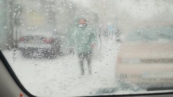 Pohled z předního skla auta se stěrači v zimě na rozmazané lidi siluety chůze - Záběry, video