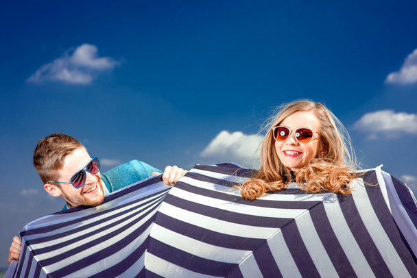 Emocional pareja escondida detrás del paraguas y divertirse en th
 - Foto, Imagen