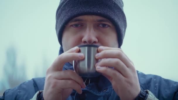 Turista de invierno o excursionista beber de taza de té caliente o café en tormenta de nieve sobre fondo neutro - Metraje, vídeo