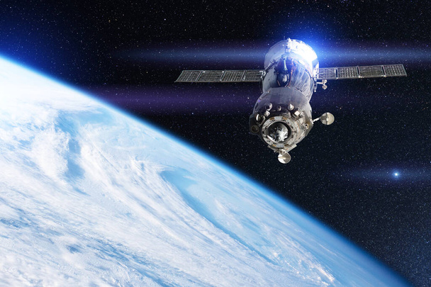 Statek kosmiczny z astronautami na pokładzie lata na orbicie ziemskiej nad wirem chmur. Elementy tego obrazu dostarczone przez NASA - Zdjęcie, obraz