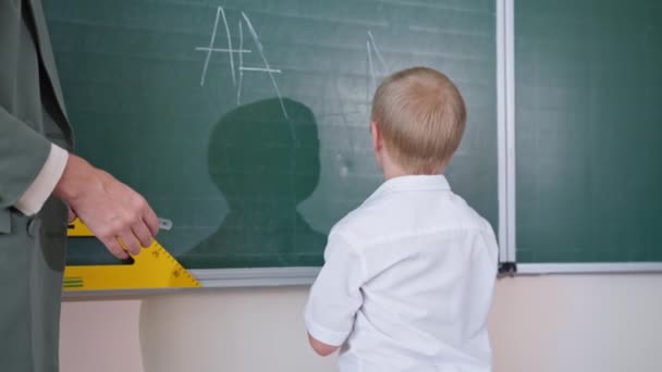 хлопчик з синдромом Даунса пише листи з білою крейдою на дошці, учень радіє успіху і дає п'ять вчителю в класі
 - Кадри, відео