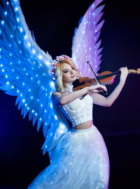 women with angel wings playing violin in neon light - Foto, immagini