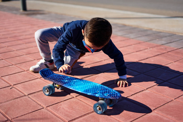 menino se levantar depois de cair em um acidente de skate em uma ciclovia. ele usa uma máscara para se proteger - Foto, Imagem