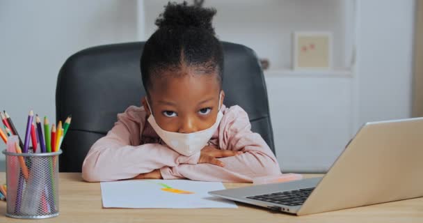 Retrato de colegiala cansada afroamericana niño usa mascarilla siente agotamiento estrés de las tareas domésticas duras sufre de insomnio y aburrimiento dormir en la mesa en casa en el aula sintiéndose mal - Metraje, vídeo