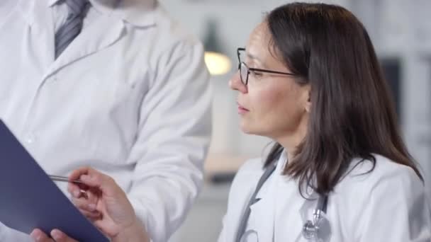 Especialistas en pulmón masculino y femenino modernos pasan la jornada laboral mirando las inyecciones de rayos X de varios pacientes - Metraje, vídeo