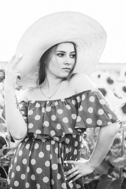 Woman in dress with polka dots on a field of sunflowers. Close plan. Black and white photography - Photo, Image