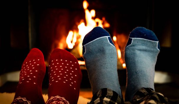 Voeten in wollen sokken voor een warme open haard op een koude winters avond. Ondiepe scherptediepte. Hoge kwaliteit foto - Foto, afbeelding