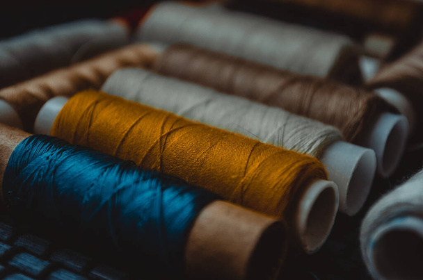 Retro naaiwerk: schaar op maat, snijmes, vingerhoed, houten draadspoelen, kussen voor het opnemen van spelden, stoffen en naaiaccessoires. - Foto, afbeelding