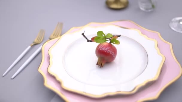 Assiettes élégantes de forme inhabituelle, décorées de grenade et couverts sur une table de banquet de mariage - Séquence, vidéo