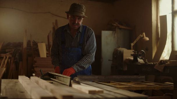 Hombre mayor usando torno de madera en taller de carpintería. Artesano haciendo productos de madera - Foto, Imagen