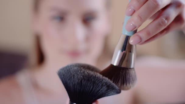 Mujer joven usando cepillo y polvo mientras hace maquillaje. - Metraje, vídeo