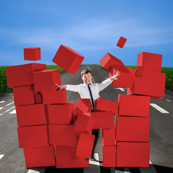 Деловой человек ломает стену из коробок красных коробок на дороге
 - Фото, изображение