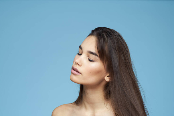 brunette with bare shoulders cosmetics close-up skin care blue background - Zdjęcie, obraz